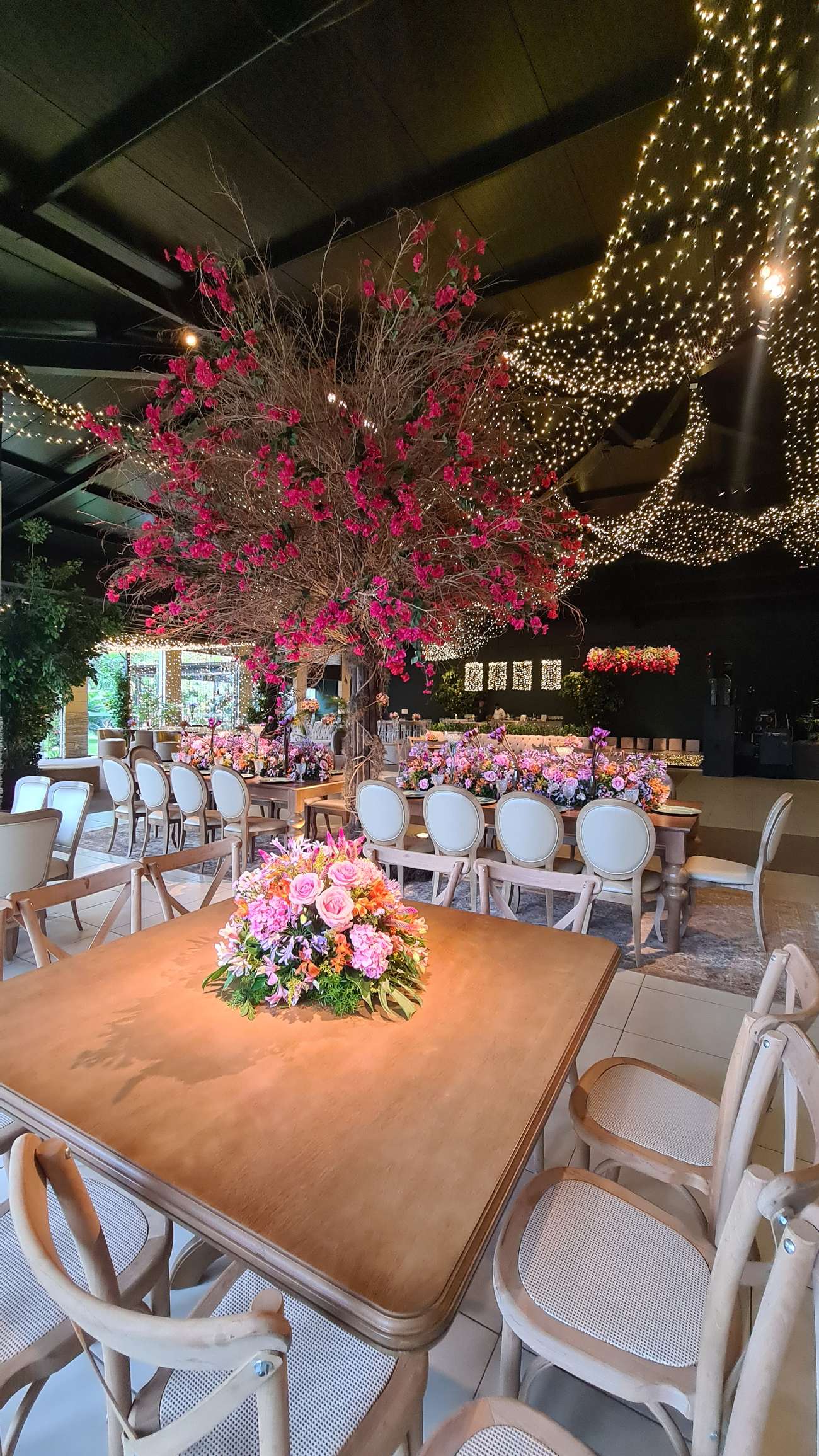 Mesas decoradas com centros florais altos, decoração própria da casa